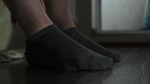 Man Removing Socks in Bedroom Interior