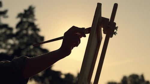 Silhouette Artist Painting at Sunset in Nature