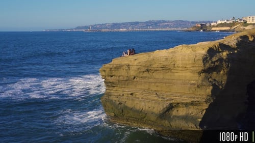 Relaxing Couple on Steep Waterfront Cliff Waiting for the Sunset in San Diego, CA