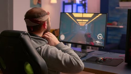 Young Adult Gamer Plays Video Game at Computer