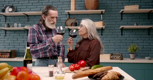 Senior Couple Toasts with Red Wine in Kitchen