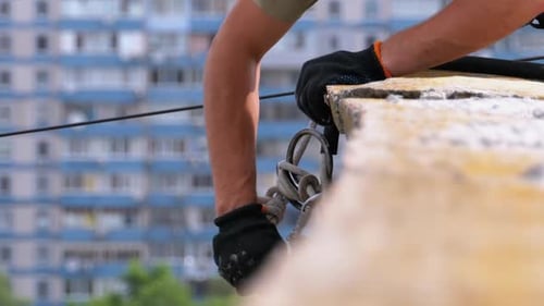 Industrial Climber in Equipment on Edge of Roof Prepares To Go Down on the Ropes