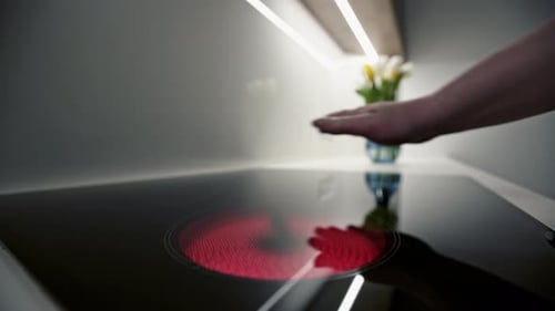 Hand Turns on Induction Cooktop in Modern Kitchen