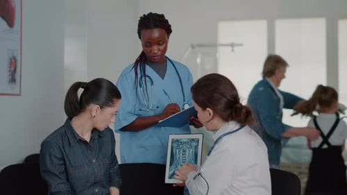 Close Up of Multi Ethnic Team Explaining x Ray Diagnosis on Tablet