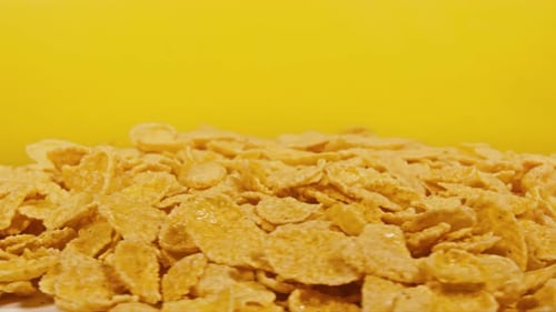 Golden Corn Flakes Pile Close Up on Yellow