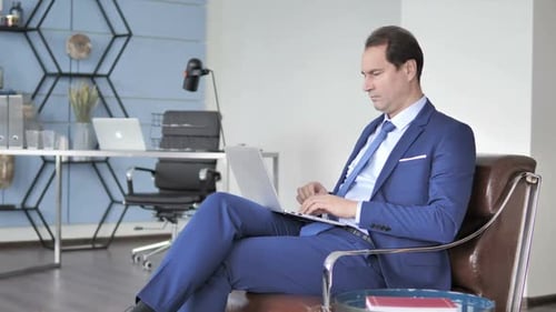 Man Works on Laptop in Modern Office