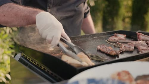 Man In Gloves And An Apron Turns Meat On Barbecue
