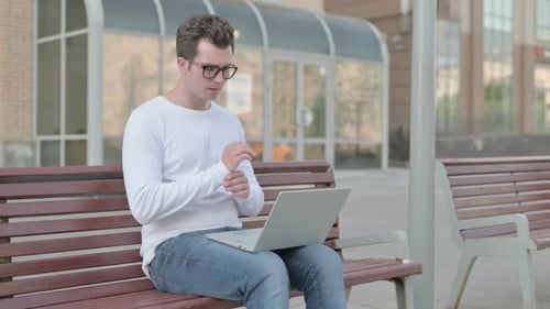 Man Typing on Laptop While Sitting on Bench