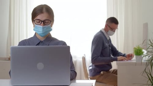 Business people in protective masks work in the office using computers.
