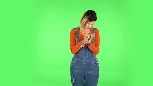 Girl Stands and Thinks, Then Intently Writes with Pencil in Notebook. Green Screen