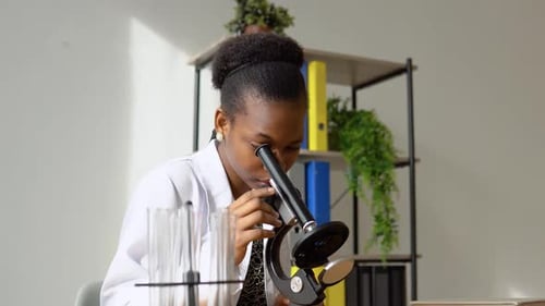 Young Woman Scientist Using Microscope in Lab