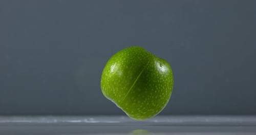 Granny Smith Apple, malus domestica, Fruit falling on Water against Black Background, Slow Motion 4K
