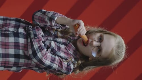 Child Eating a Carrot Wearing Glasses in Studio