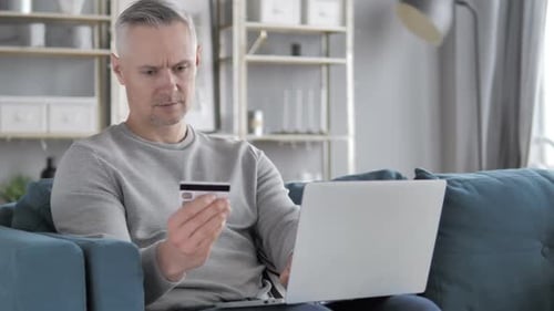 Man Uses Laptop with Credit Card at Home