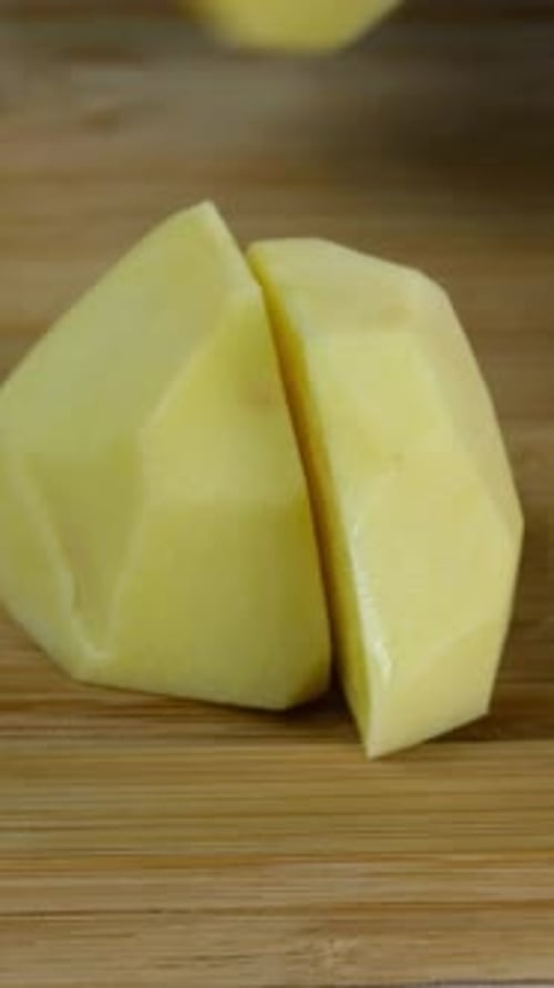 Le chef a tranché les pommes de terre crues en gros morceaux avec un couteau de cuisine pour faire de la purée de pommes de terre