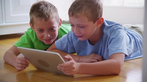 Two Young Boys Play on Tablet Together