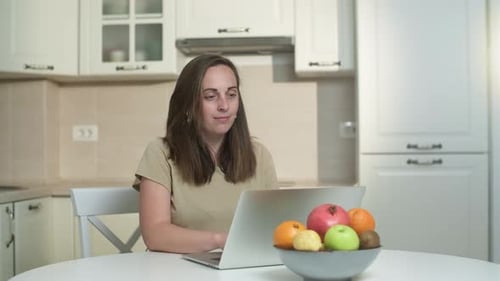 Woman Working on Laptop in Bright Kitchen