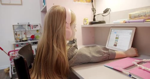 Girl with Headphones Using Tablet at Desk