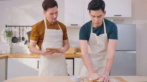 Asian young LGBTQ male gay family enjoy bake bakery in kitchen at home.