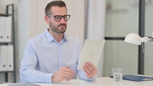 Man Talking on Tablet Video Call in Office