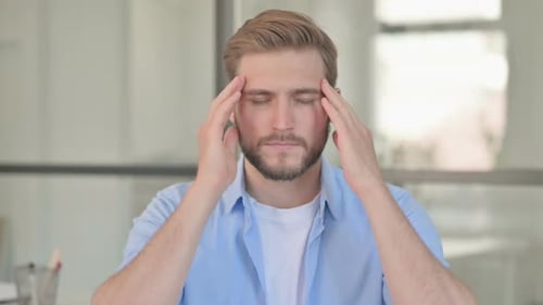 Stressed Man Rubbing Temples and Eyes in Office