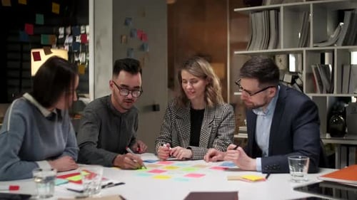 Business Team Brainstorming Using Color Labels On Table In Office. Man Is Writing On Stickers