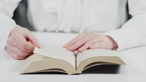 Woman Turns Pages of Book at Desk
