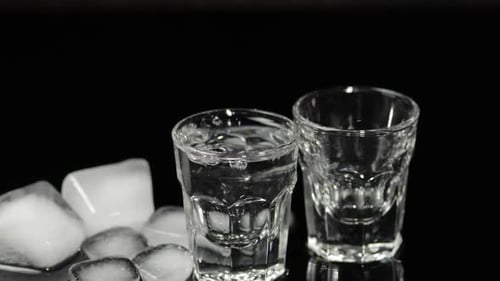 Pouring Clear Liquid into Two Shot Glasses