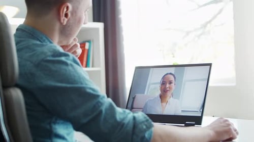 Man on Video Call with Colleague on Laptop
