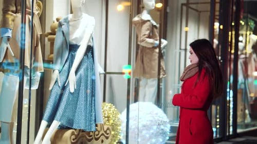 Femme regardant la vitrine d'une boutique de mode