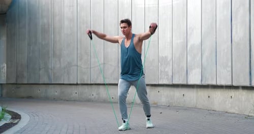 Muscular Man Exercising with Resistance Band Outdoors