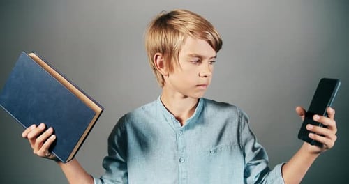 Boy Compares Book and Cellphone