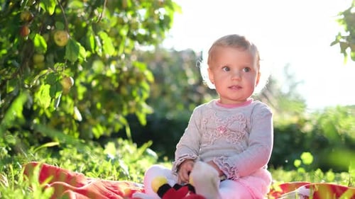 Kleines Mädchen mit blonden Haaren ruht im Garten ein Kind im Freien in der Nähe eines Apfelbaums