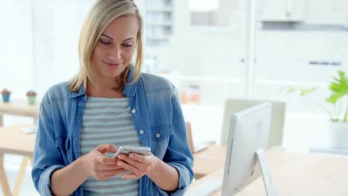 Woman Types on Smartphone in Bright Office
