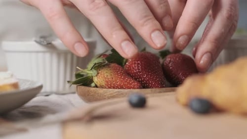 Adding Strawberries to a Bowl of Delicious Fruit