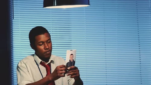 Close-up of Mixed-race Young Detective Showing Photos of a Person To Suspect Criminal