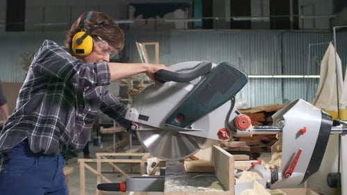 Young Adult Using a Chop Saw in a Factory