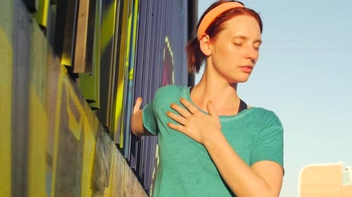 Red Haired Woman Stretching Against Graffiti Wall