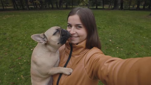 Young Woman Holding Puppy in Autumn Park