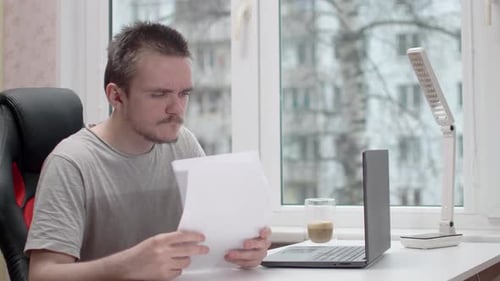 Man Reads Document and Celebrates at Desk