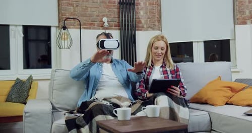 Couple Relaxing at Home with VR Headset and Tablet