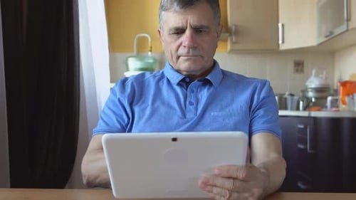 Man Using Tablet at Table in Home