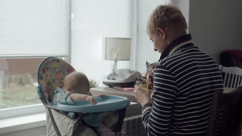 Infant being fed in high chair at home