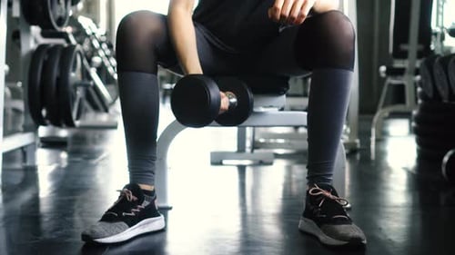 Young Woman in Sportswear Doing Seated Dumbbell Concentration Curl Bicep Exercise at the Gym