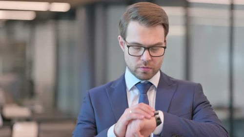 Serious Businessman Checking Watch in Modern Office