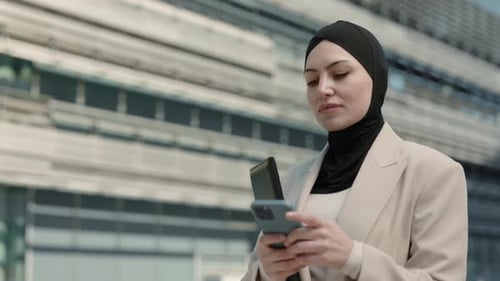 Arabian Woman Using Smartphone While Walking Outdoors