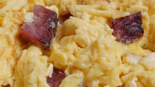 Fried beaten eggs with bacon on plate close-up 4K 2160p 30 fps UltraHD tilting footage - Slow tilt o