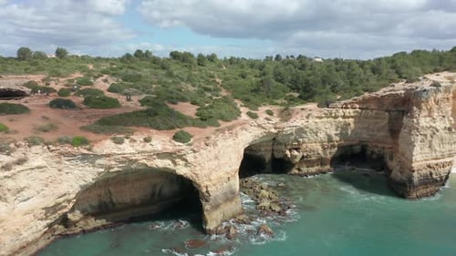 Drone pulling away from beautiful shoreline with caves and cliffs