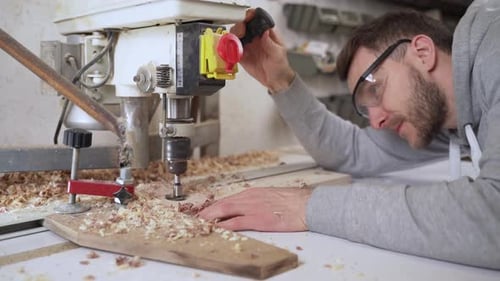 Man Using Drill Press in Workshop