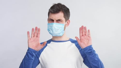 Man in Face Mask Holds Hands Up to Stop